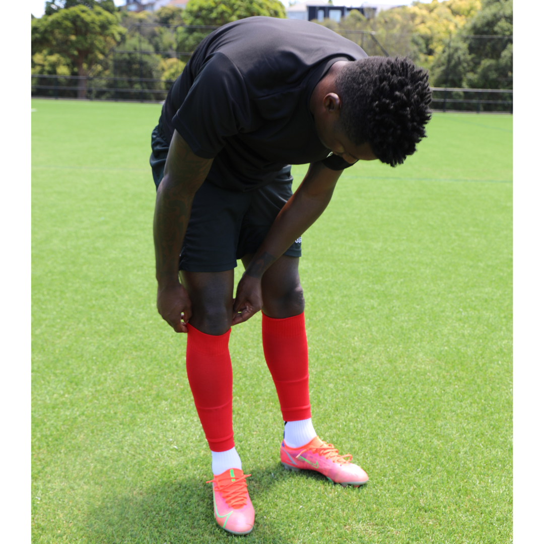 Soccer player wearing footless sock. Football player wearing sock sleeve for compression and comort.