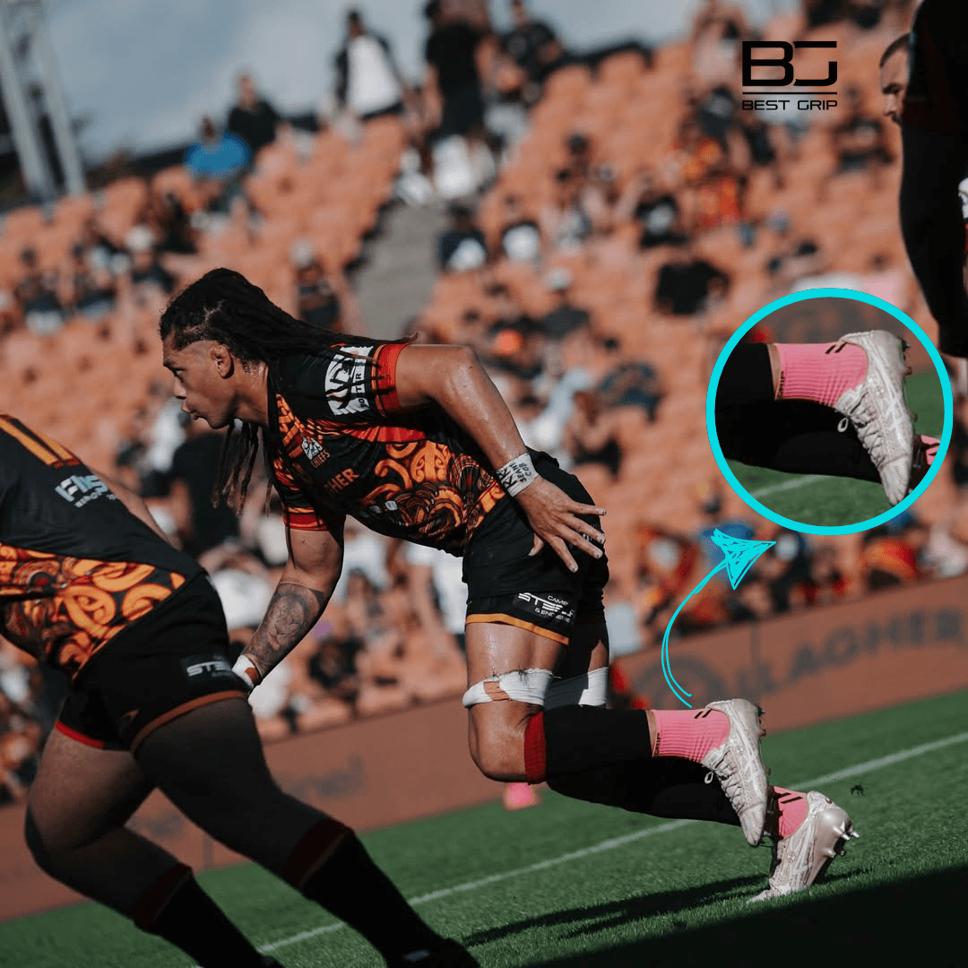 Rugby player in action on a field with a close-up of pink socks and shoes, featuring 'Best Grip' socks.